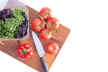 Preparing a healthy leafy green salad with farm fresh sweet bell pepper, tomatoes and assorted...