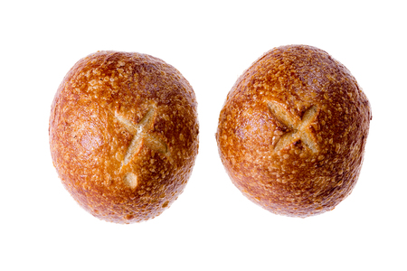 Two crusty round fresh sourdough rolls or buns decorated with crosses displayed side by side on a white background viewed from the topの写真素材