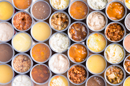 Colorful background of neatly arranged rows of opened cans of assorted soup viewed full frame from above in a food abstract still lifeの写真素材