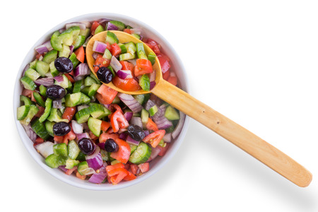 Fresh colorful Turkish shepherd salad with olives served in a round bowl with a wooden serving spoon as a healthy accompaniment to a meal, overhead on whiteの写真素材