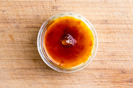 Creme brulee topped with crunchy flamed caramelised sugar served in a glass bowl viewed from...