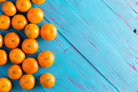 Colorful fresh orange mandarins laid out on a rustic cracked blue painted wooden picnic table viewed from above with copy spaceの写真素材