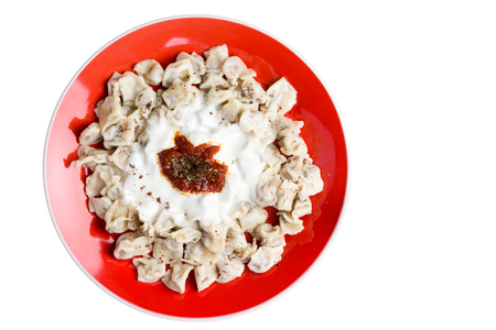 Plate of fresh homemade Turkish manti dumplings made with spicy minced lamb or beef wrapped in pasta and fried served topped with Greek yogurt and caramelised tomato sauceの写真素材