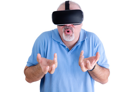 Man in blue polo shirt reacts to wearing virtual reality glasses by grabbing at the air with both...