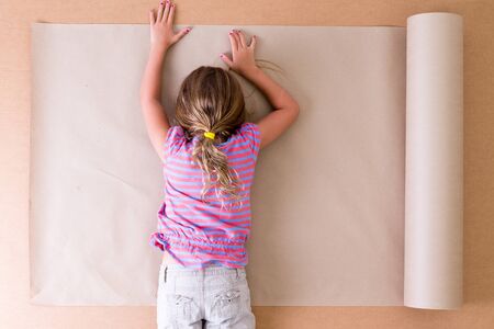 Depressed young little girl artist lying face down on the paper as she struggles to come up with original ideas and creative designs, overhead viewの写真素材