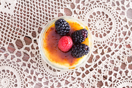 Freshly prepared creme brulee with red and black raspberries on vintage doilies.の写真素材