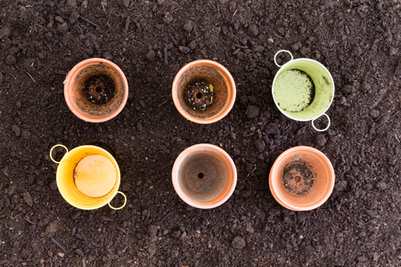 Four clay pots and two metal ones in rows of three on rich black earthの写真素材