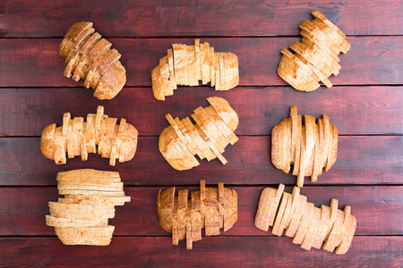 Top down view on nine sliced loaves of speciality wheat and white flour breads in staggered...
