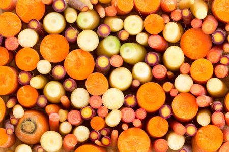 Colourful background of assorted sliced carrots in orange, white and purple forming an abstract pattern of rounds in a full frame food textureの写真素材