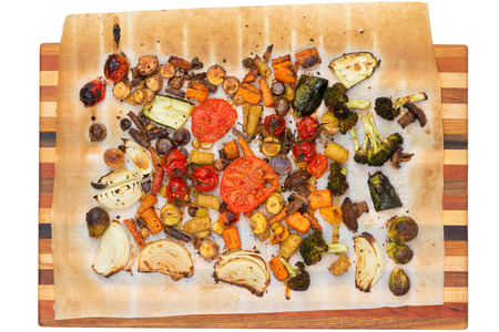 Top down view of recently grilled or roasted tomatoes, broccoli, squash, carrots, mushrooms, brussels sprouts and peppers over towel on wooden cutting boardの写真素材