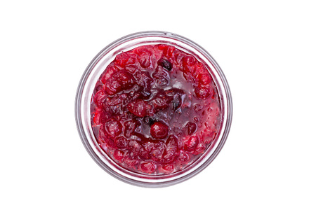 View from above of delicious and tangy bright red cranberry sauce in single glass bowl over isolated backgroundの写真素材