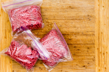 Fresh ground beef in resealable plastic bags ready to go into the freezer for storage on a wooden...