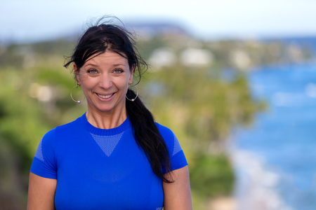 Fun young woman pulling a goofy face giving the camera a beaming cheesy grin as she poses at Diamond Head, Oahu, Hawaiiの写真素材