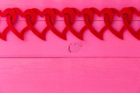 Romantic border of red hearts linked in a chain over a vivid pink background with copy space for your Valentines or anniversary greeting or invitationの写真素材