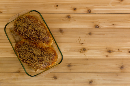 Two delicious homemade wholegrain bread buns fresh from the oven in a glass dish over a wooden background with knot texture and copy spaceの写真素材