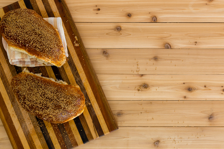 Two fresh loaves of speciality wholegrain bread on a decorative striped wooden bread board over a wooden table with copy space viewed from aboveの写真素材