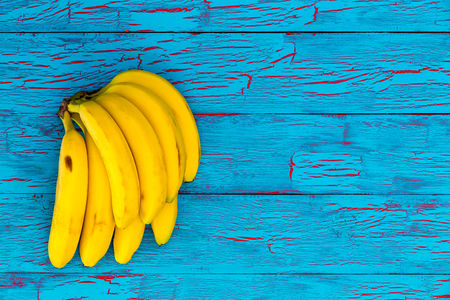 Bunch of healthy ripe yellow bananas on an exotic crackle paint turquoise blue wood background with copy spaceの写真素材