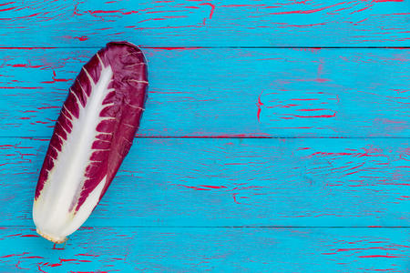 Single head of fresh leafy radicchio or Italian chicory forming a side border over a blue crackle...