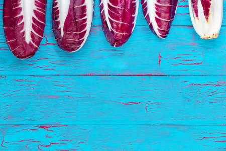 Top border of five fresh radicchio heads with the last pointing the opposite direction showing the...