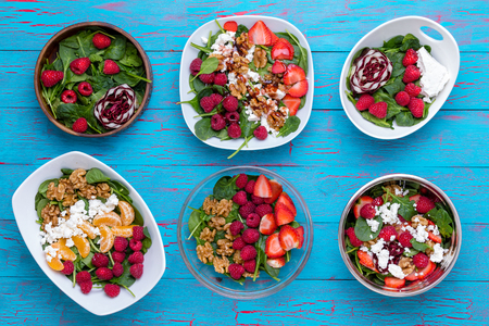 Conceptual high angle view of bowls with fruit salads against blue wooden backgroundの写真素材