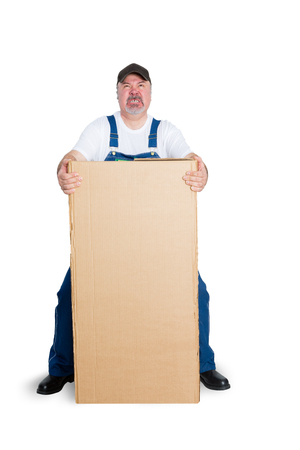 Delivery man standing behind large cardboard box against white backgroundの写真素材