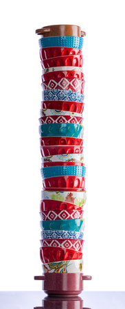 Tall stack of colorful clean baking ramekins for cooking individual portions in the oven on a reflective table over a white background in a vertical panoramaの写真素材