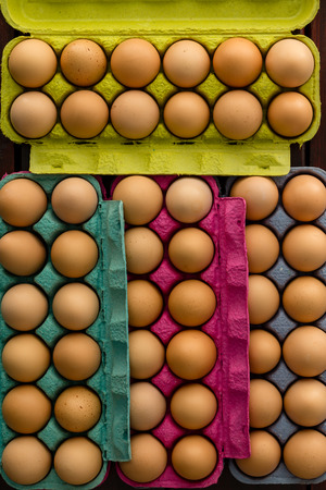 Colorful full cardboard boxes of fresh farm eggs viewed from above in full frameの写真素材