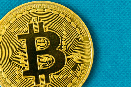 Golden coin with Bitcoin sign logo in close-up macro on turquoise blue background with copy spaceの写真素材