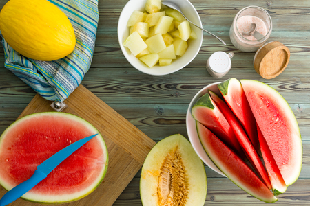 Healthy dessert for a summer picnic with diced fresh canary melon and wedges of juicy watermelon viewed from above in a flat lay still lifeの写真素材