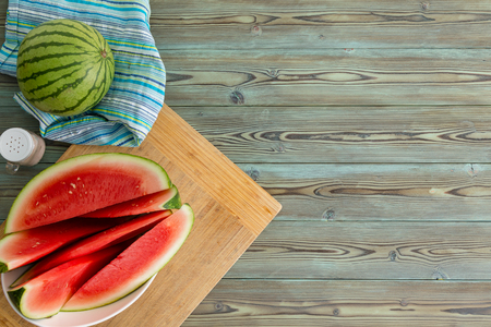 Refreshing juicy sliced fresh watermelon on a plate on a cutting board served on a wooden picnic table for a summer dessert with copy space from aboveの写真素材