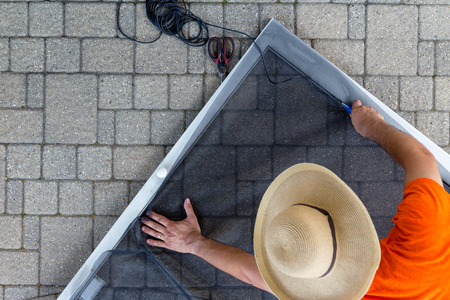 Man wearing hat replacing old material in porch doorの写真素材