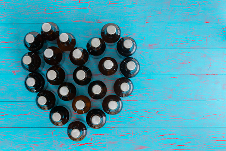 Heart shaped still life of capped beer bottles viewed top down on a blue picnic table conceptual of I Love Beer and summer parties with copy spaceの写真素材
