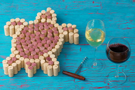 Creative design of a sea turtle from red and white wine bottle corks on a textured turquoise blue wood background with glasses of wine and a corkscrewの写真素材