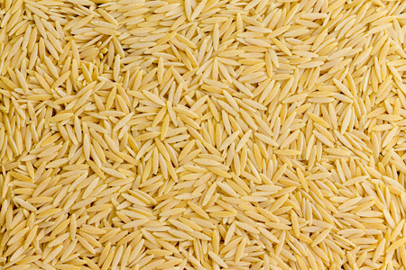 Background texture of dried Italian orzo pasta shaped like grains of rice and used in the preparation of soups in a full frame viewの写真素材