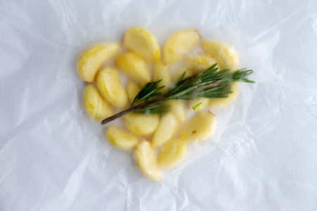 Rosemary infused fresh whole garlic cloves in a sous vide bag ready to go in to waterの写真素材