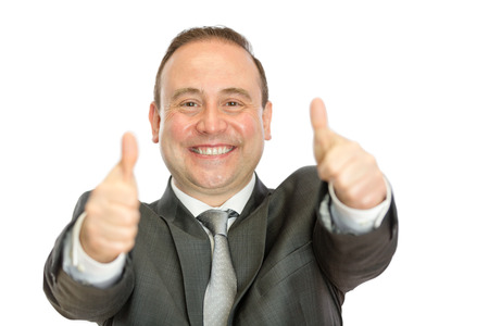 A happy, enthusiastic, mature businessman giving thumbs up signals with both hands on a white  with copy space.の写真素材