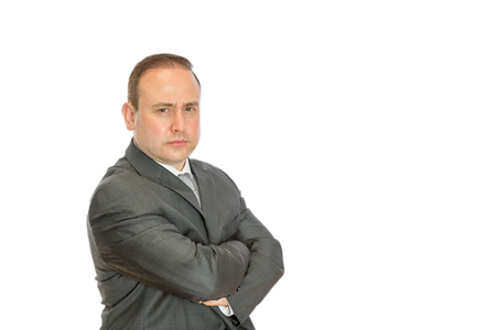 An angry, stern businessman with crossed arms on a white  with copy space.の写真素材