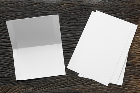 Blank portrait mock-up paper. brochure magazine isolated on brown wooden table, changeable background / white paper isolated on woodの写真素材