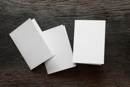 Blank portrait mock-up paper. brochure magazine isolated on brown wooden table, changeable background / white paper isolated on woodの写真素材