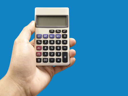 Male hand with calculator isolated on blue backgroundの写真素材
