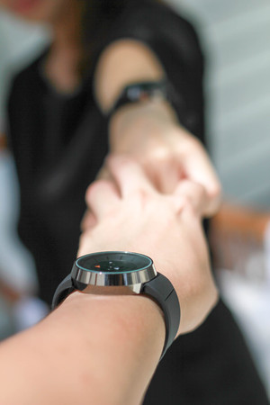 The pair of hands holding each other and both like to wear the same watches.の写真素材