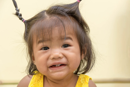 A ten-month-old girl wearing a yellow coat, Happy smile with just four teeth that she has and drooling.の写真素材