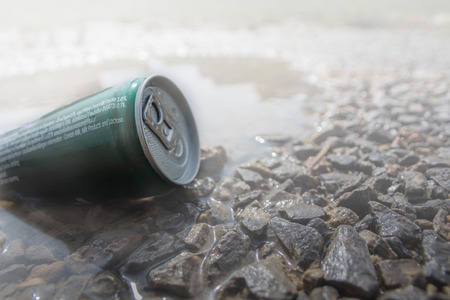 Instant coffee to packed in tins is placed in water and has a rock foreground and white light in background with bokeh.の写真素材