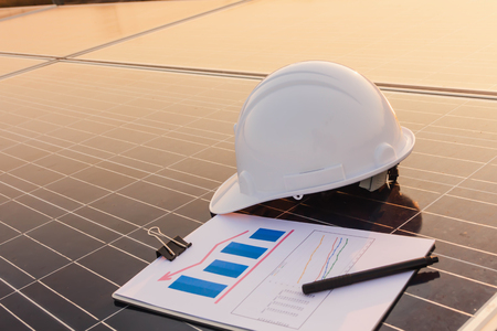 Engineers are examining the performance graph of energy production from solar panels that are alternative energy and which is the concept of sustainable resources.の写真素材