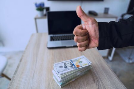 Man's hand showing thumb up - like sign with many money on background, Businessmen who work actively...