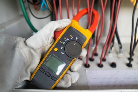 Workers use clamp meter to measure the current of electrical wires produced from solar energy for confirm to normal current.の写真素材