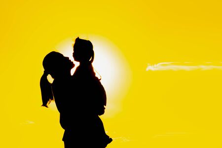The family silhouette of the mother and child standing watch the sunset and the sky in orange in evening.の写真素材