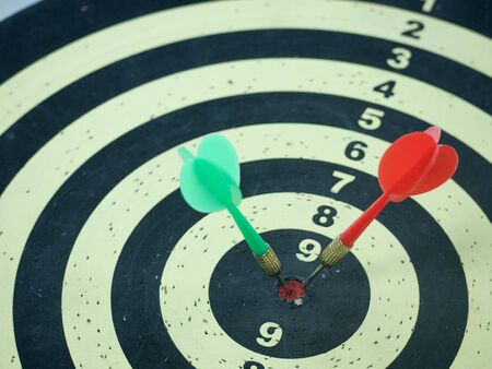 Red and Green dart target arrow hitting on bullseye which is the ultimate goal that everyone wants,...