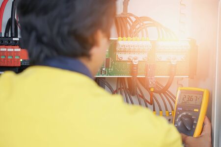 Workers use Multimeter to measure the voltage of electrical wires produced from solar energy for...