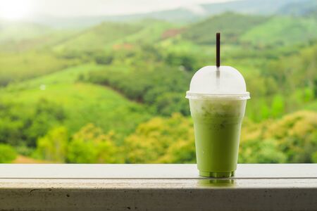 Iced green tea with warm sunshine in the morning has a mountain background.の写真素材